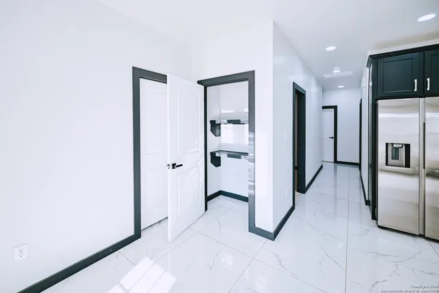 a view of a kitchen with refrigerator and an empty room