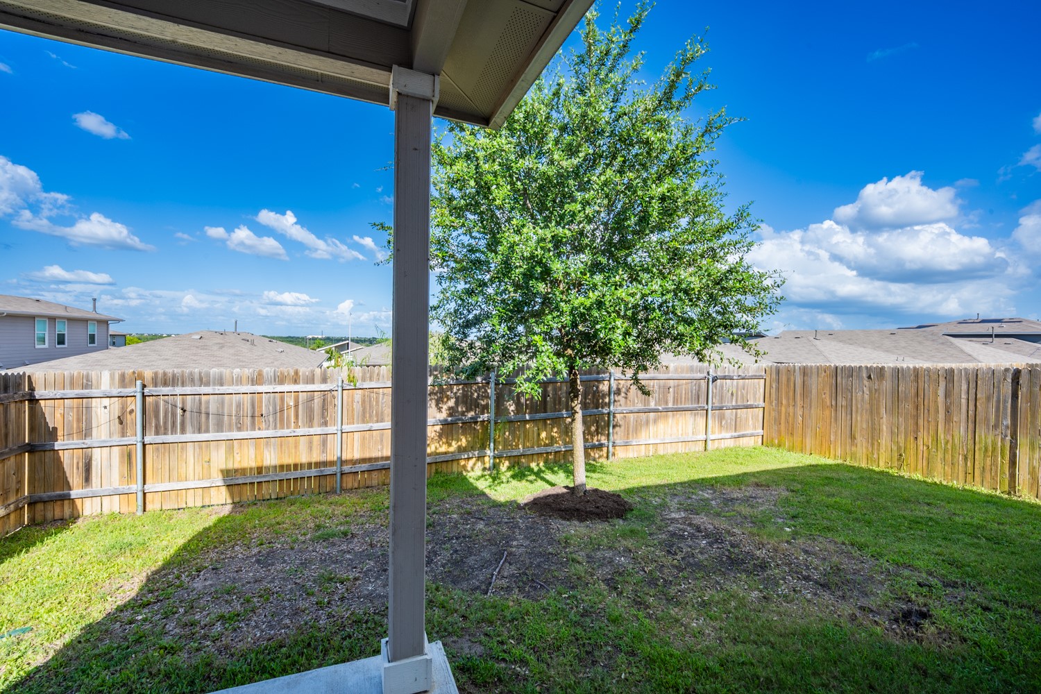 10801 Meris Lane Austin, TX 78754 - Photo 18 of 18 A private, fenced backyard offers a verdant space for recreation and relaxation beneath a vibrant blue sky.