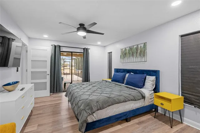 a bedroom with a bed a couch and a flat tv screen on dresser