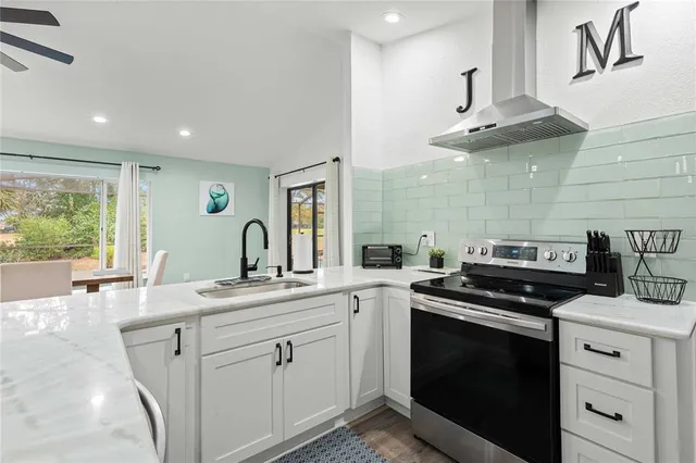 a kitchen with stainless steel appliances granite countertop a sink a stove and a wooden floors