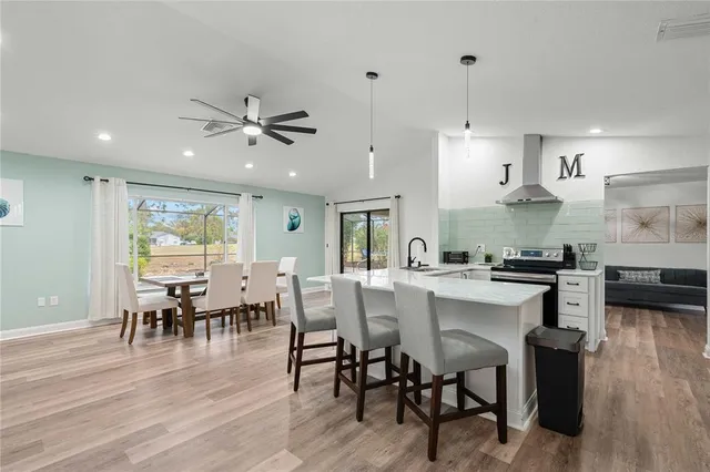 a kitchen with stainless steel appliances granite countertop a stove a refrigerator a kitchen island a dining table and chairs with wooden floor
