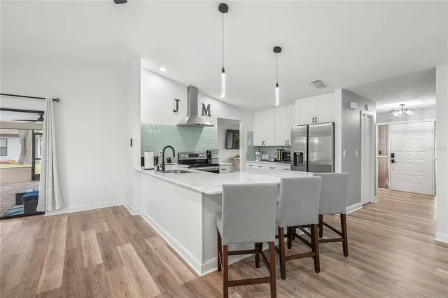 a kitchen with stainless steel appliances granite countertop a sink a stove a refrigerator and island with wooden floor