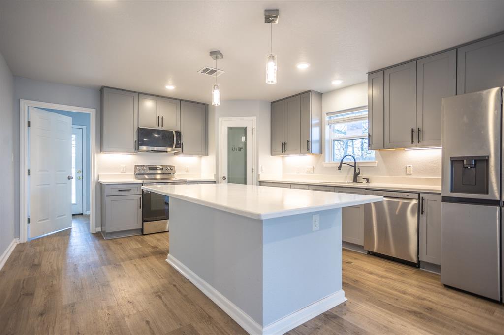 815 Ritchey Street Gainesville, TX 76240 - Photo 4 of 18 a kitchen with kitchen island granite countertop a sink cabinets and stainless steel appliances