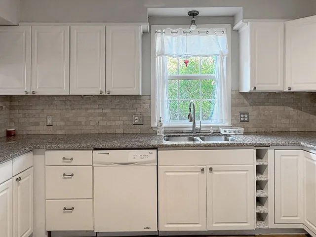 a kitchen with granite countertop white cabinets and a window