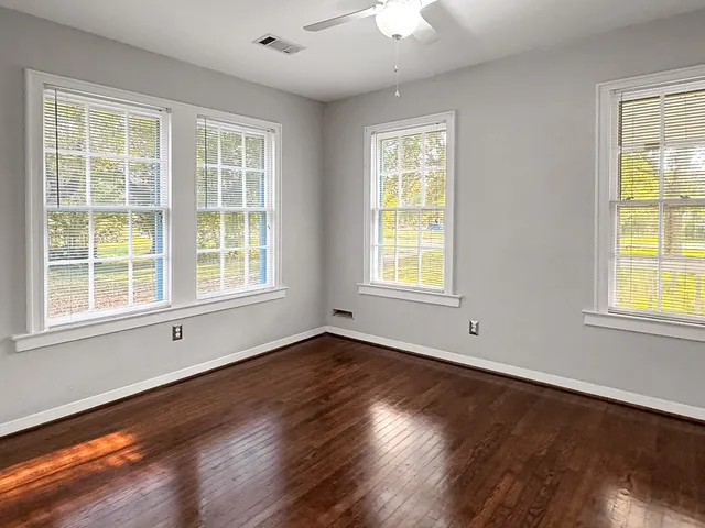 an empty room with wooden floor and windows