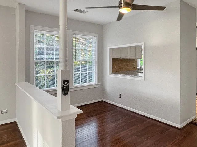 a view of an empty room with wooden floor and a window
