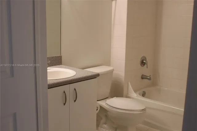 a bathroom with a granite countertop toilet and a bathtub