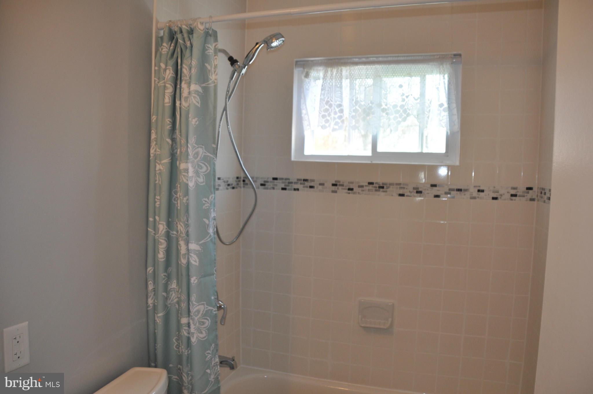 3837 Bayville Road Baltimore, MD 21220 - Photo 5 of 14 a bathroom with a granite countertop shower a toilet and a window
