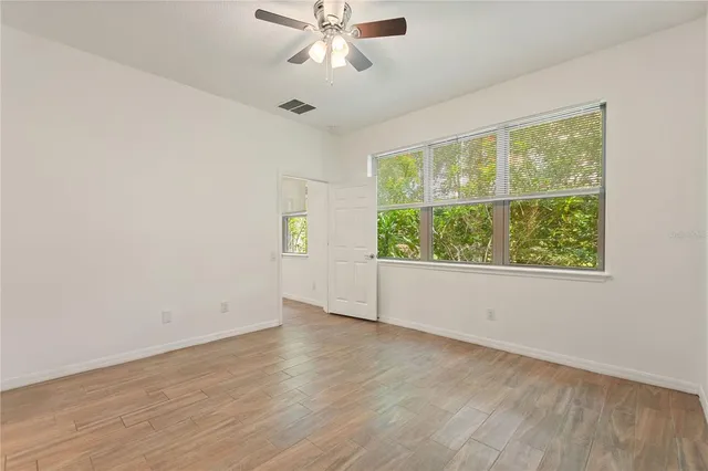 a view of an empty room with wooden floor and a window