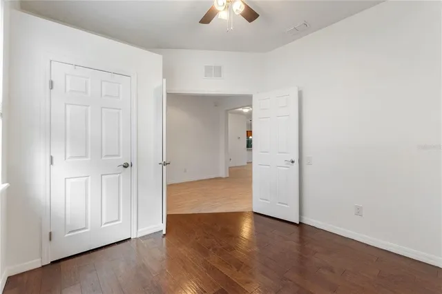 an empty room with wooden floor closet and windows