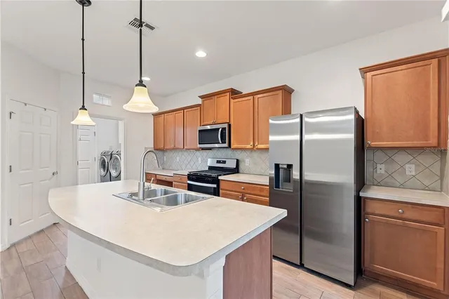a kitchen with stainless steel appliances a refrigerator a sink a stove a kitchen island and chairs