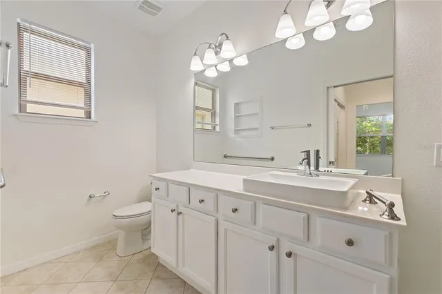 a spacious bathroom with a granite countertop toilet a sink and a mirror