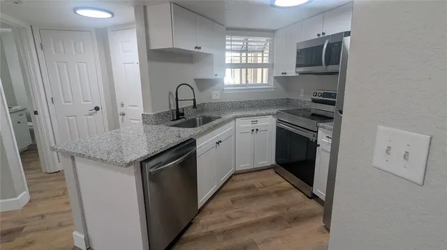 a kitchen with a sink cabinets and wooden floor