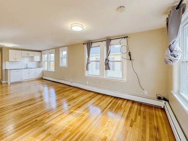 a view of an empty room with a window and wooden floor