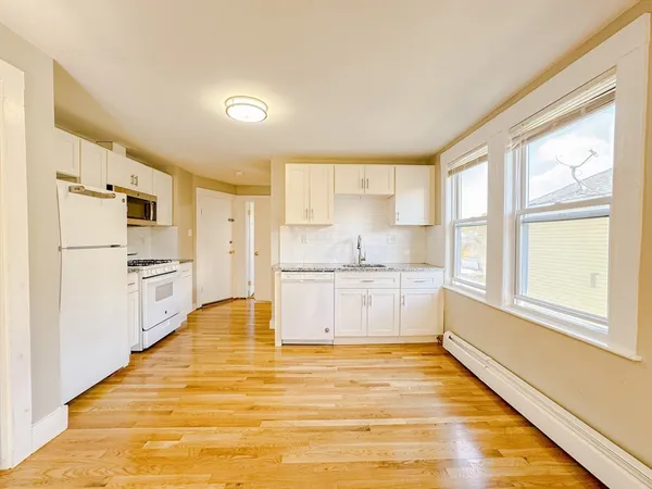 a large white kitchen with cabinets and wooden floor