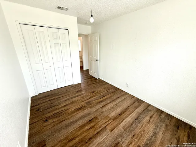 an empty room with wooden floor chandelier fan and windows