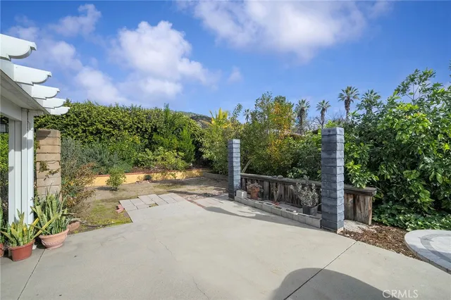 a backyard of a house with table and chairs plants and large tree