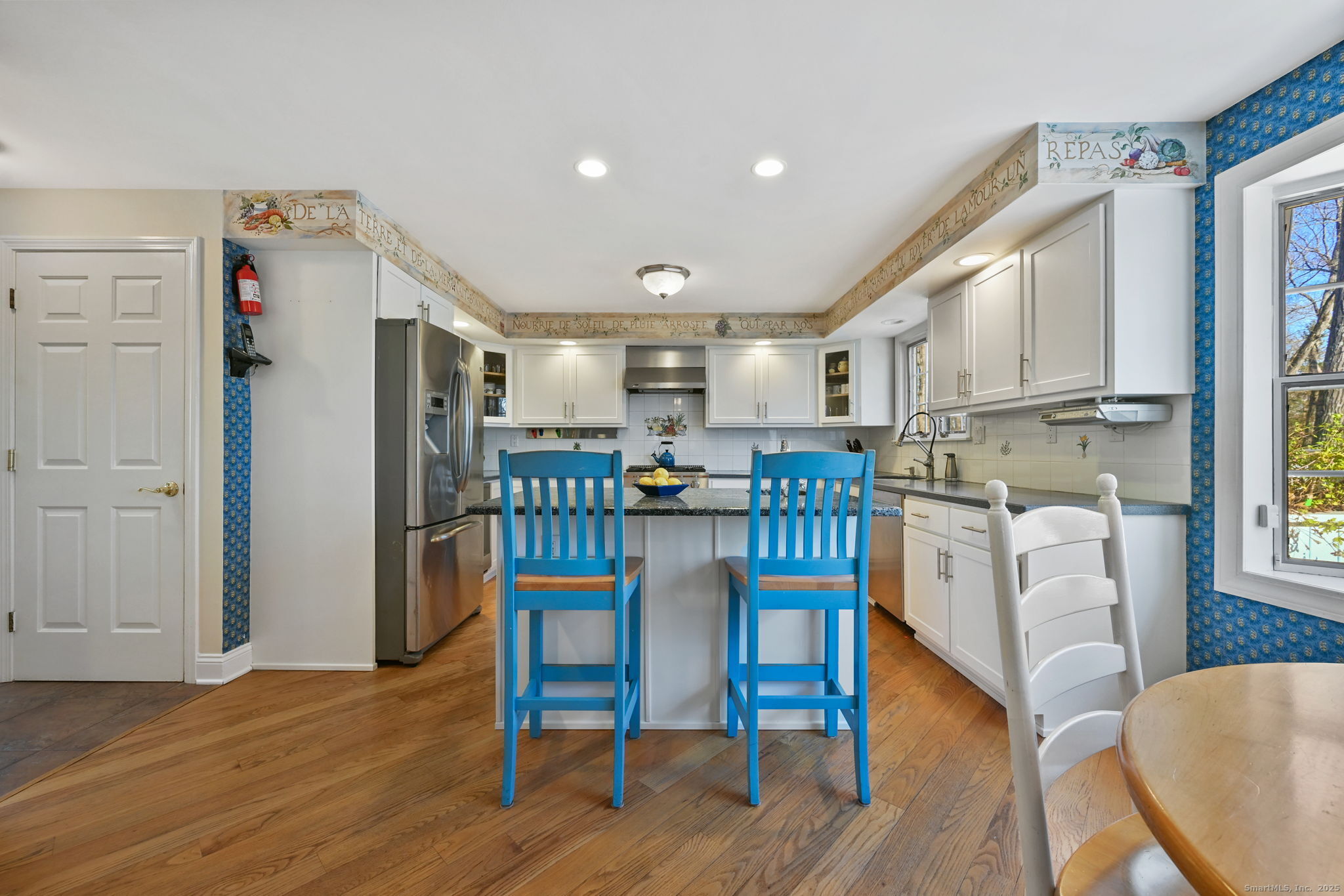 269 Thunder Lake Road Wilton, CT 06897 - Photo 8 of 26 a kitchen with stainless steel appliances kitchen island granite countertop a refrigerator a stove a microwave oven a dining table and chairs with wooden floor