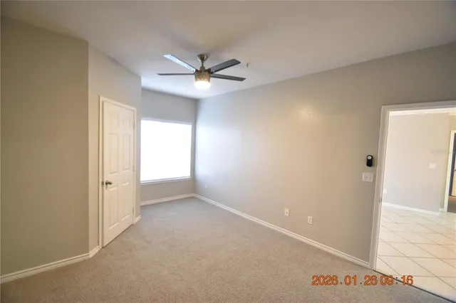 an empty room with windows and ceiling fan