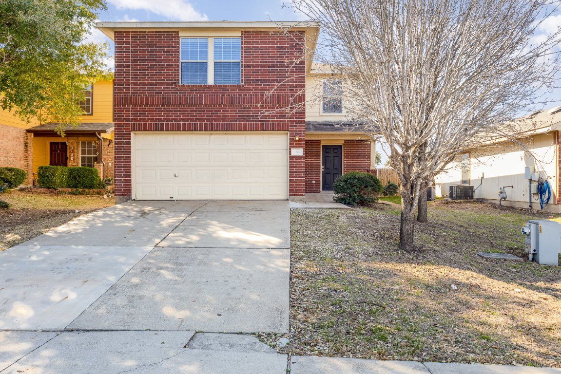 Traditional home featuring a garage, central AC, brick siding, and driveway
