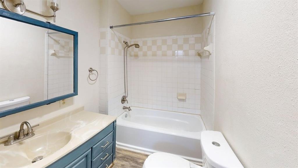 224 West Hull Street, Unit B Denison, TX 75020 - Photo 11 of 13 a bathroom with a granite countertop sink mirror toilet and bathtub