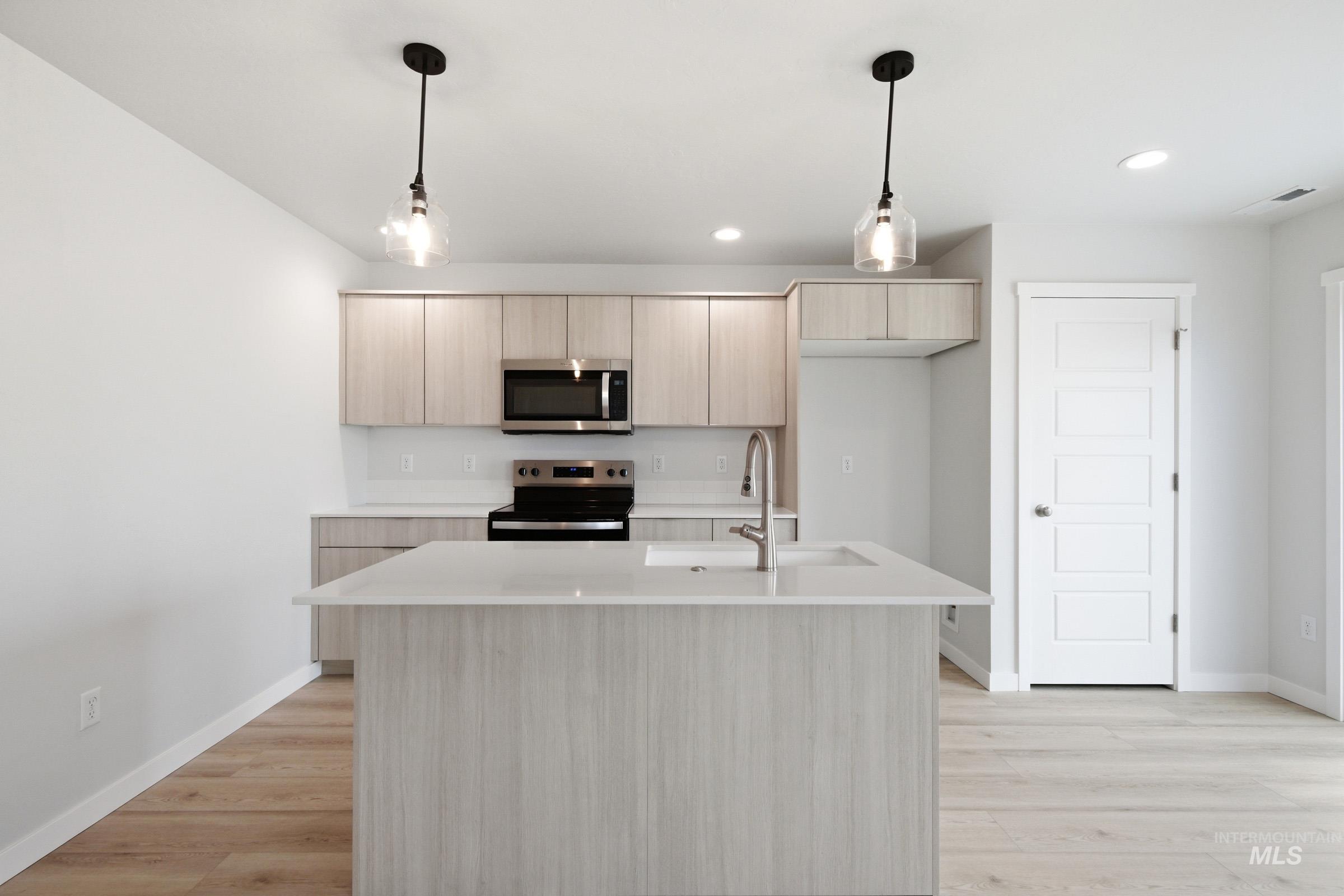 10770 Rutland Street Caldwell, ID 83605 - Photo 11 of 22 Kitchen featuring wood-finish cabinetry, stainless steel appliances, a center island with a sink, and pendant lighting