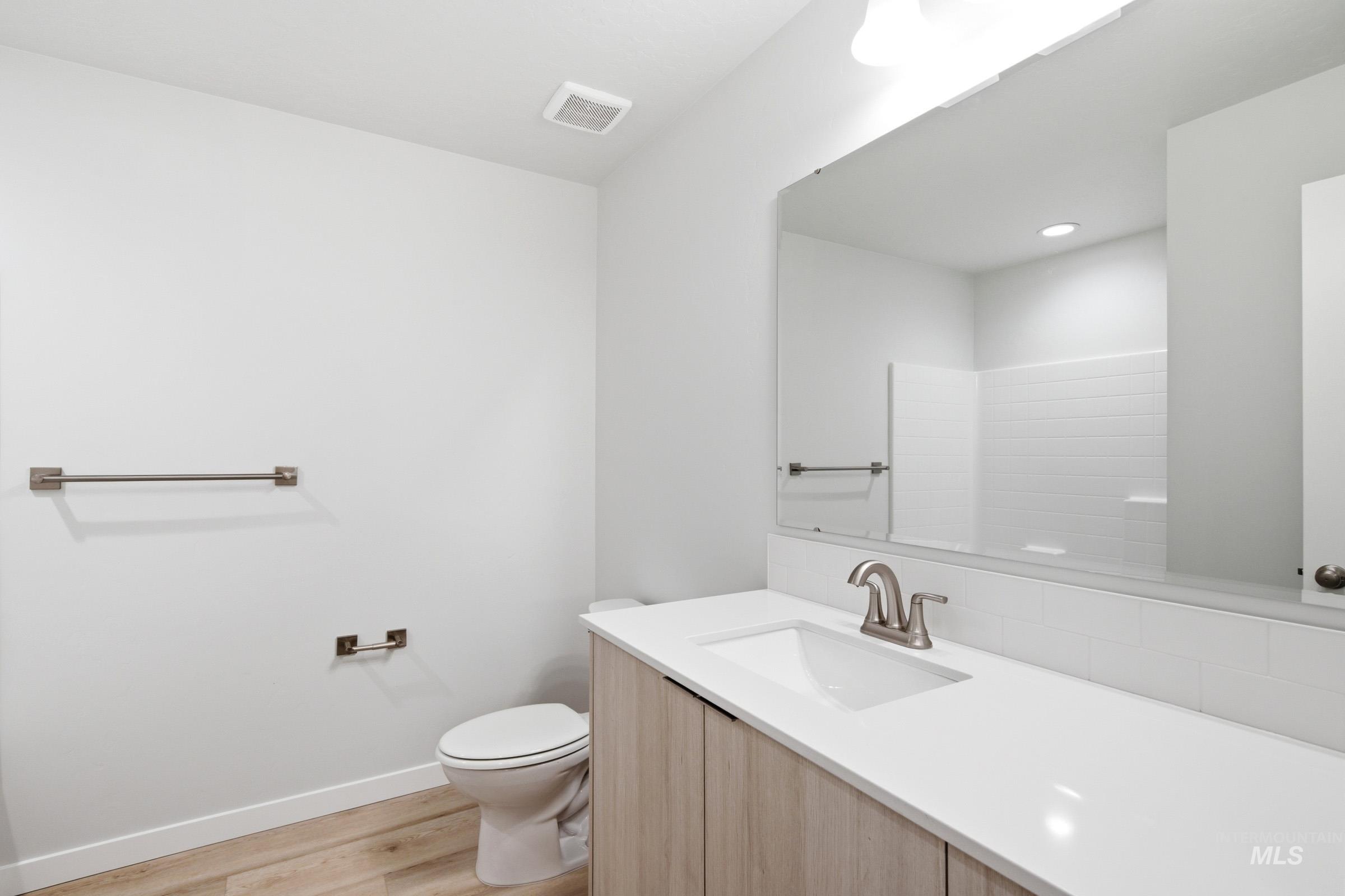 10770 Rutland Street Caldwell, ID 83605 - Photo 16 of 22 Bathroom featuring a light wood-finish vanity with a white countertop and integrated sink, brushed nickel faucet, and a large wall-mounted mirror