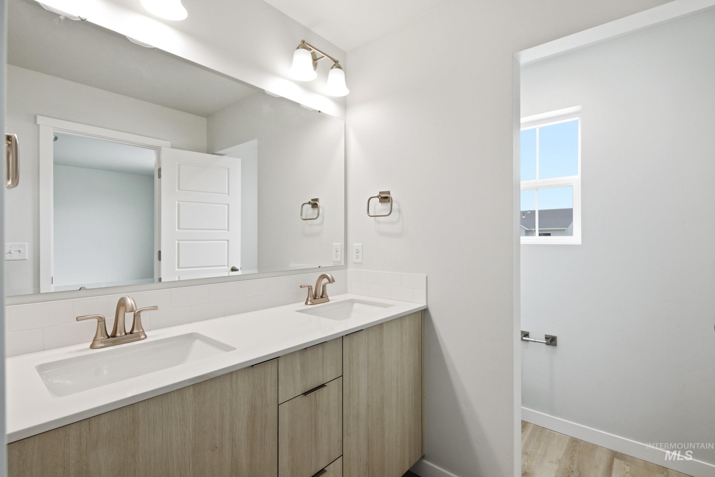 10770 Rutland Street Caldwell, ID 83605 - Photo 20 of 22 Double vanity featuring light wood-finish cabinetry, white countertop, and dual sinks with brushed nickel fixtures