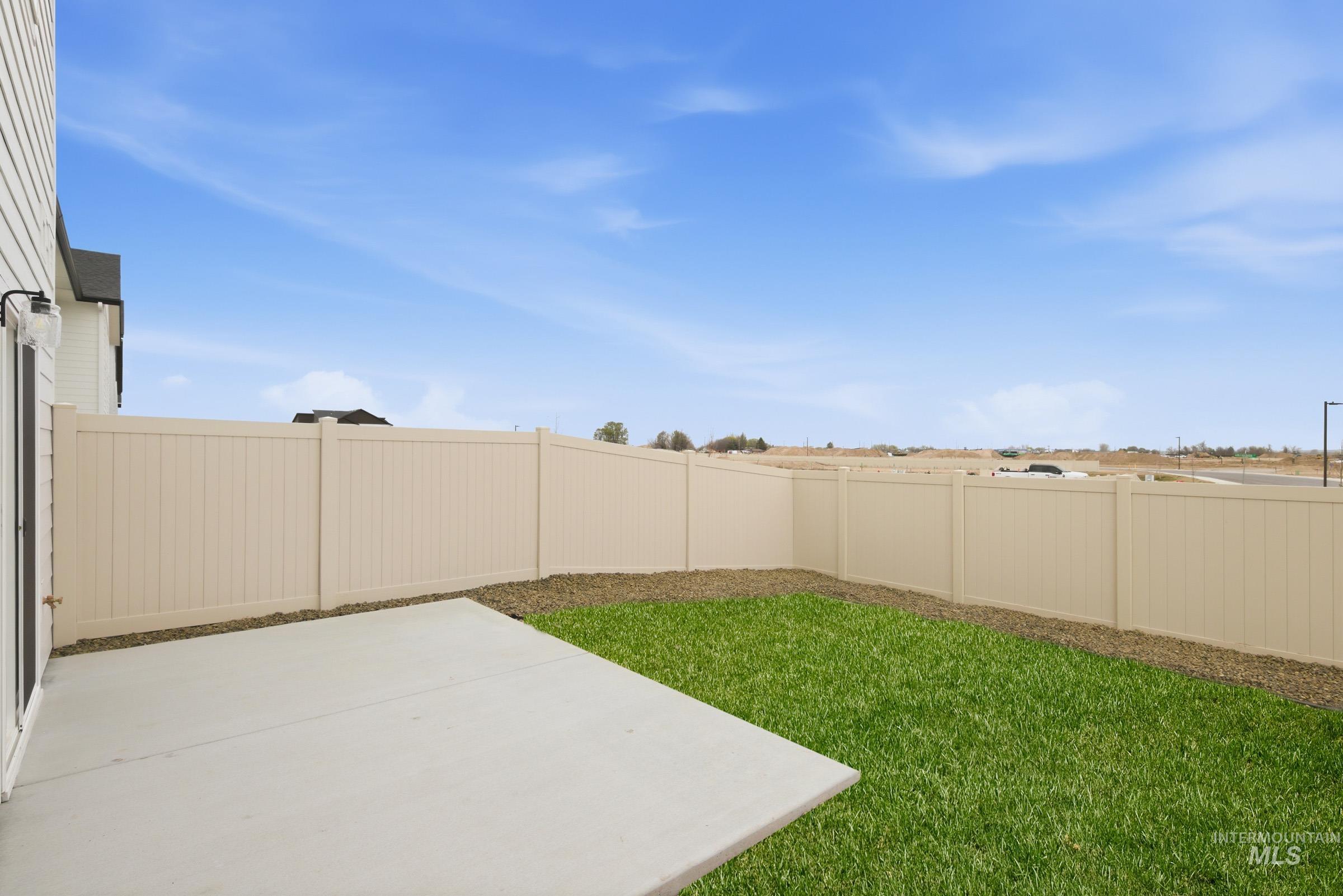 10770 Rutland Street Caldwell, ID 83605 - Photo 22 of 22 Expansive backyard featuring a concrete patio, a lush green lawn, and a light-colored privacy fence