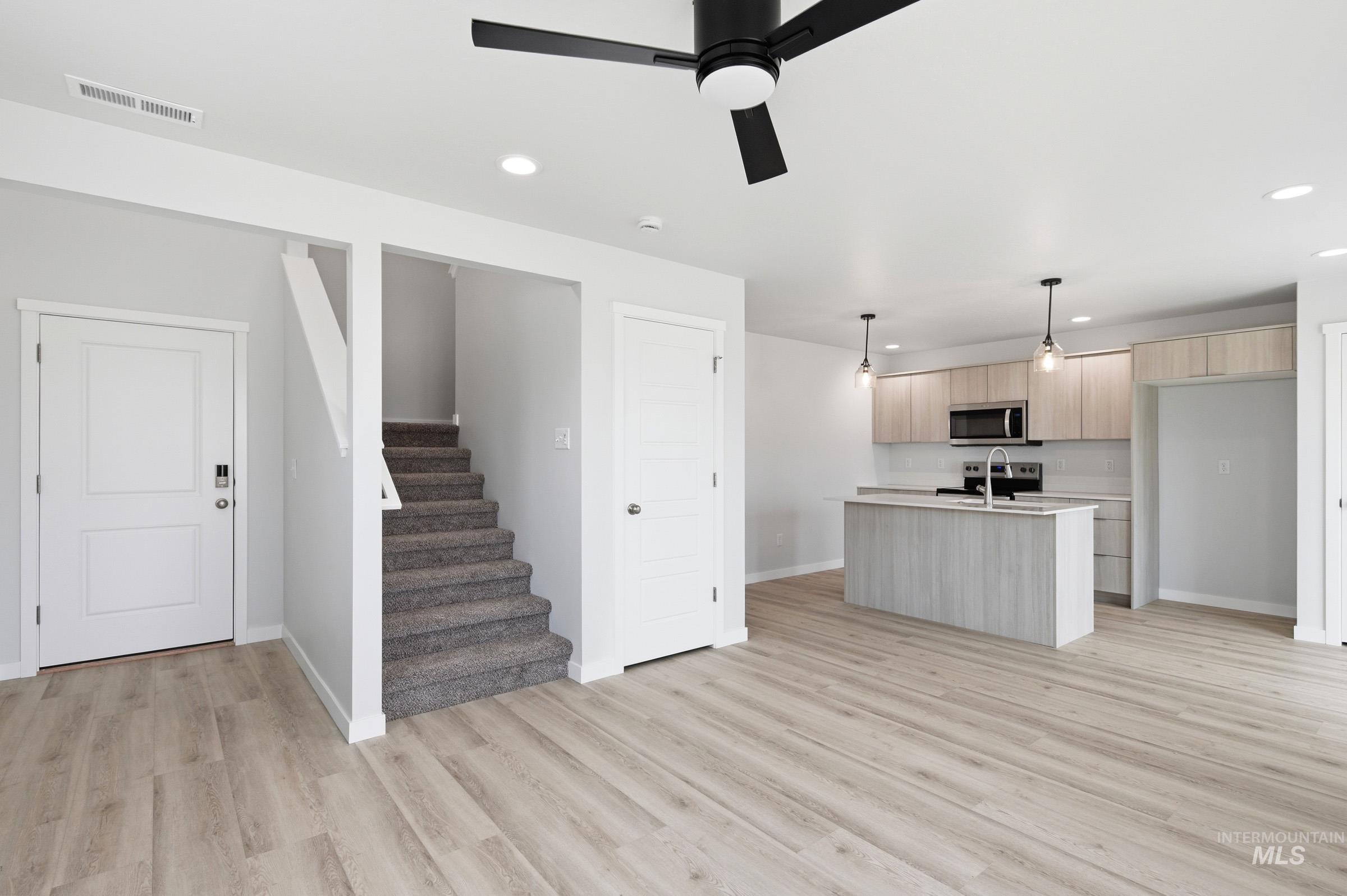 10770 Rutland Street Caldwell, ID 83605 - Photo 9 of 22 Open-concept living area featuring wood-finish flooring, a modern kitchen with light wood cabinetry and a central island, stainless steel appliances, and recessed lighting