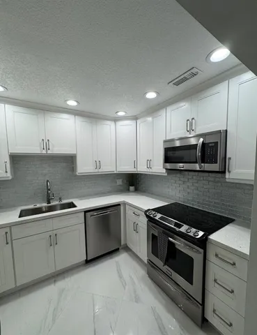 a kitchen with stainless steel appliances granite countertop a sink and stove top oven