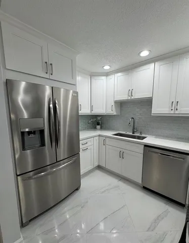 a kitchen with stainless steel appliances granite countertop a refrigerator sink and white cabinets