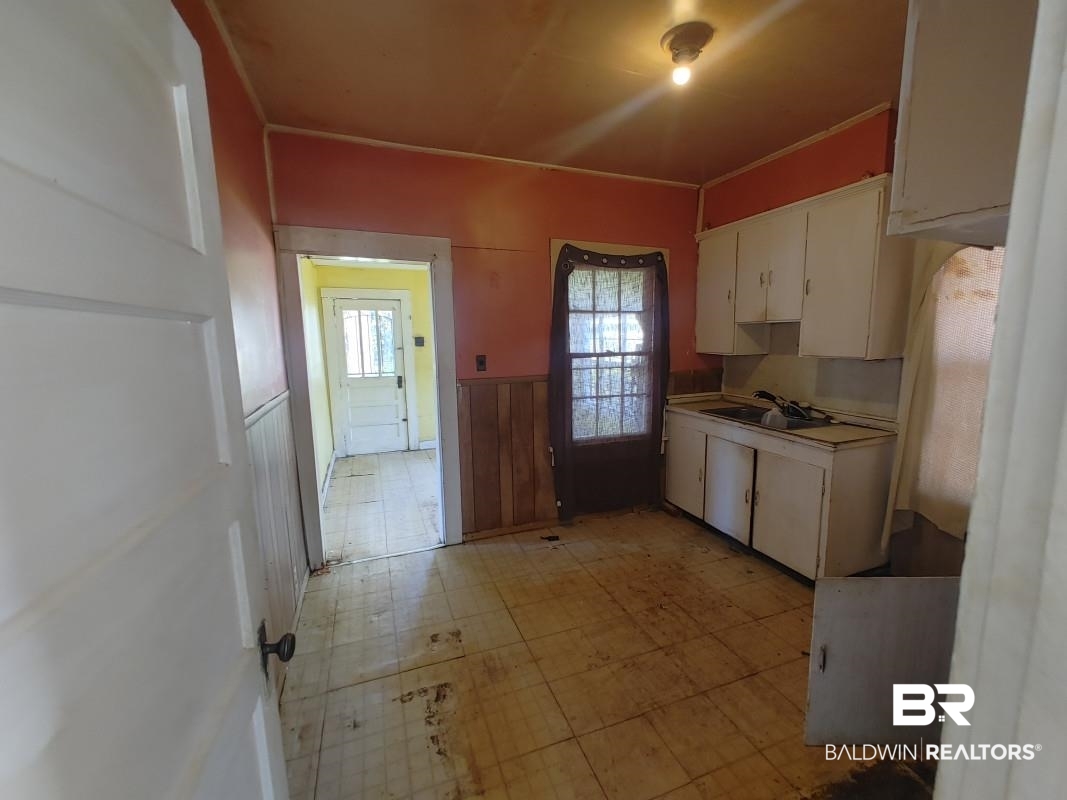 1706 Lomeroy Street Mobile, AL 36604 - Photo 19 of 24 Kitchen with white cabinets, wainscoting, ornamental molding, light floors, and a sink