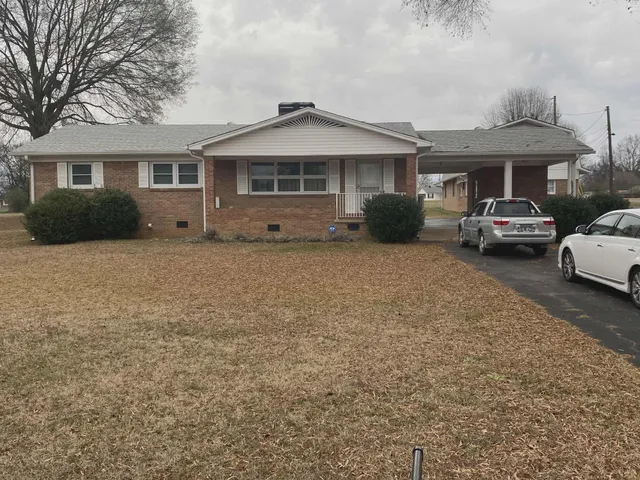 a front view of a house with a garden and parking space
