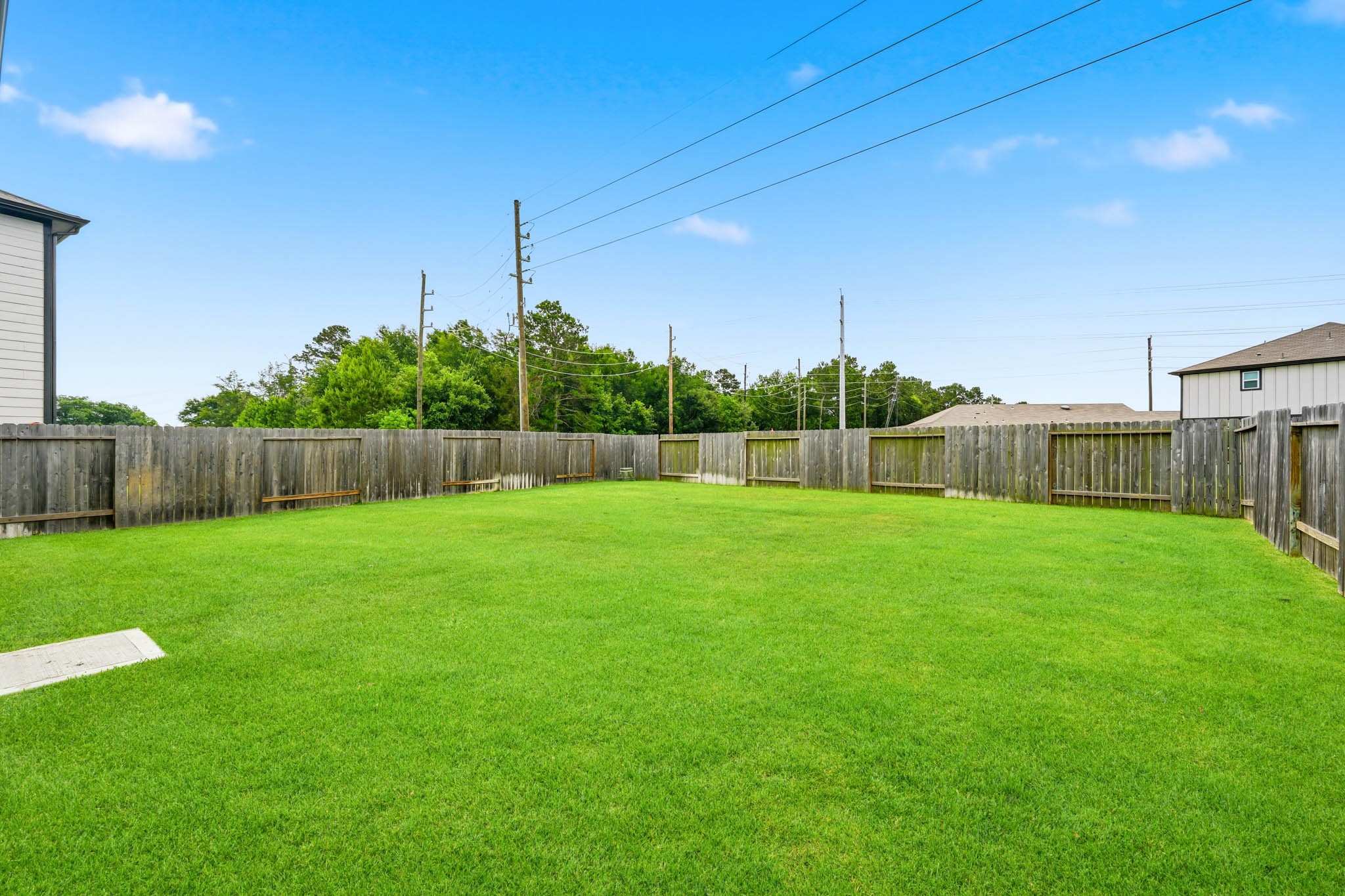 23427 Weir Box Road Hockley, TX 77447 - Photo 26 of 32 A view across the expansive 5,604 sq. ft. lot, showing a fully enclosed wood privacy fence and a vast, level lawn—perfect for kids, pets, or building your dream outdoor entertainment space.