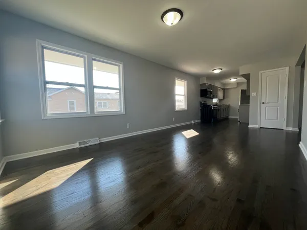 an empty room with hard wood floors and windows