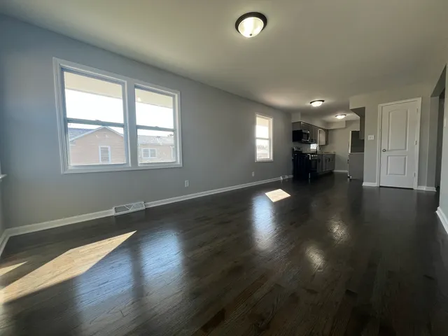 an empty room with hard wood floors and windows