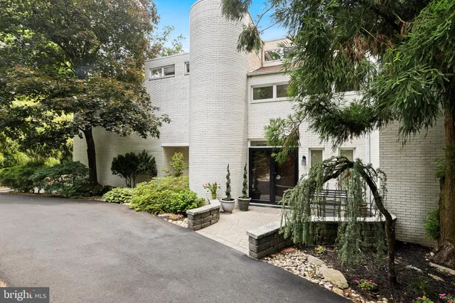 an aerial view of a house with outdoor space and trees all around