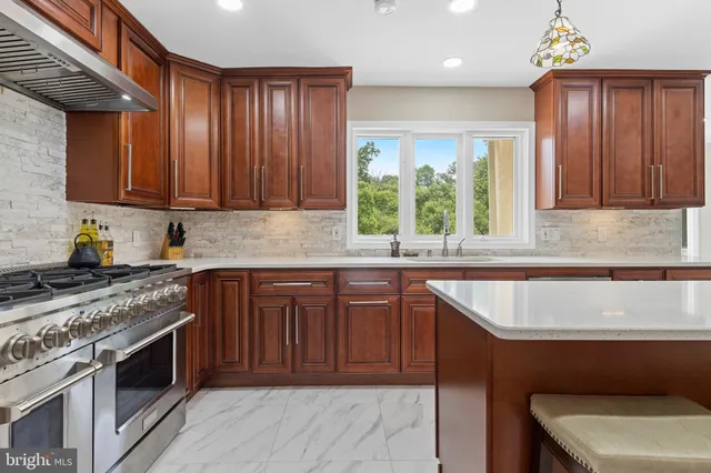 a large kitchen with stainless steel appliances granite countertop a refrigerator a sink dishwasher a oven and a dining table with wooden floor