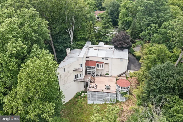 an aerial view of a house with outdoor space and trees all around