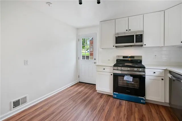 a kitchen with stainless steel appliances a white stove top oven and white cabinets