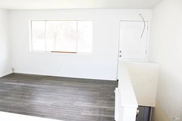 a view of a room with wooden floor and white walls