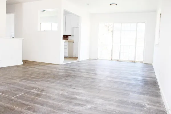 a view of an empty room with wooden floor and a window