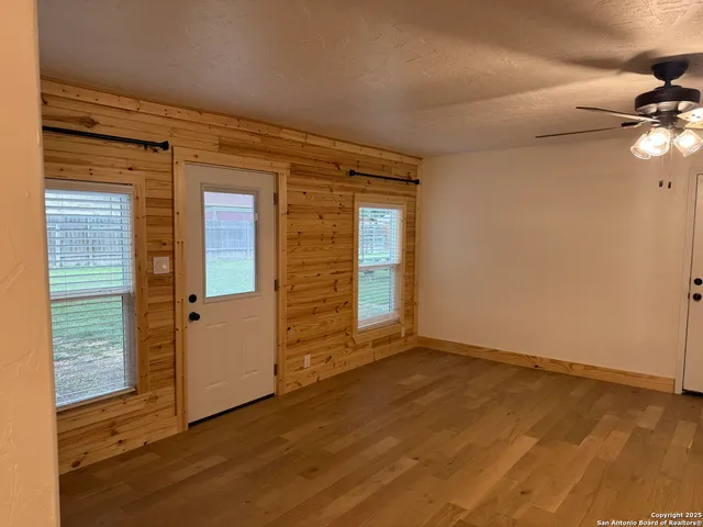 a view of an empty room with window and wooden floor