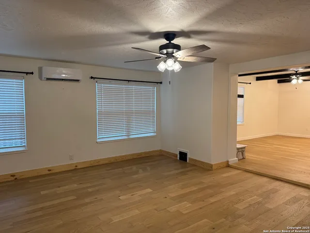 an empty room with windows and fan
