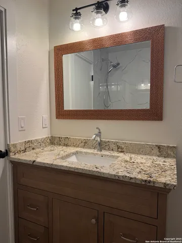 a bathroom with a granite countertop sink and a mirror