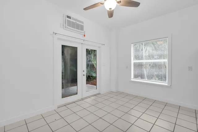 an empty room with chandelier fan and windows