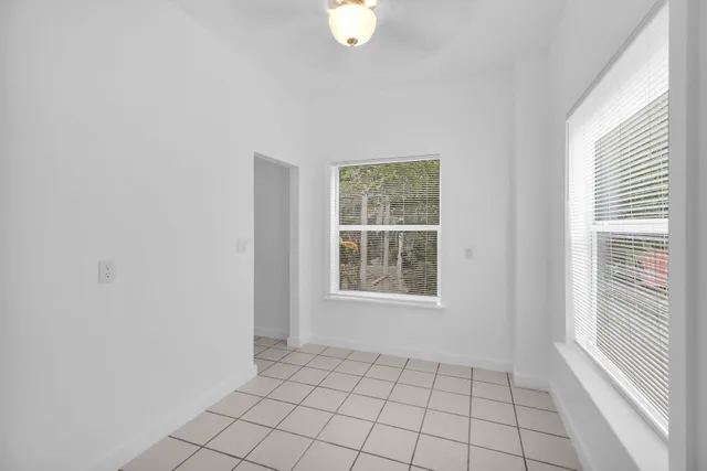 a view of an empty room with window and cabinet area