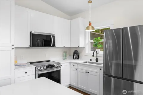 a kitchen with stainless steel appliances white cabinets and a stove top oven