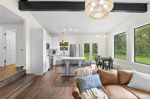 a living room with furniture kitchen view and a large window